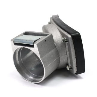 Metallic automotive throttle body sitting on a white surface, featuring a cylindrical opening and a rectangular metal plate, surrounded by mounting bolts and a black rubber seal.