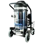 A silver industrial vacuum cleaner with a black lid and large wheels, labeled “Kerrick,” stands on a grey surface, equipped with a side handle and rear storage basket.