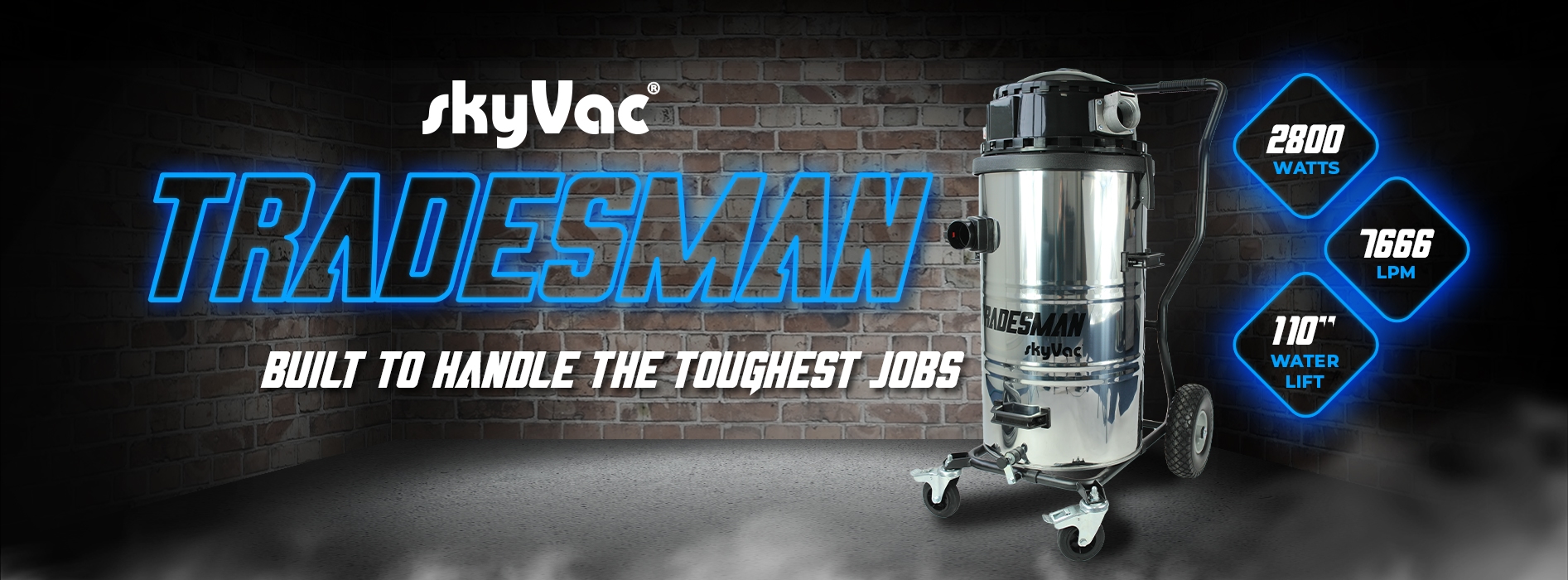 Vacuum cleaner standing on wheels against a brick wall, labeled "skyVac TRADESMAN" with specs: 2800 watts, 7666 LPM, 110" water lift, and slogan "BUILT TO HANDLE THE TOUGHEST JOBS."